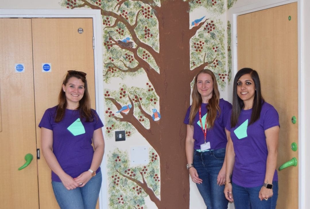Photo of three IRESS staff members Photo of three IRESS staff members in front of the tree mural in the Willow Ward end of life room.